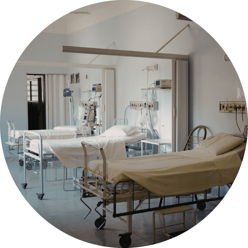 Chambre d'hôpital moderne avec trois lits médicalisés équipés de draps beige, moniteurs et perfusions, sol en carrelage gris