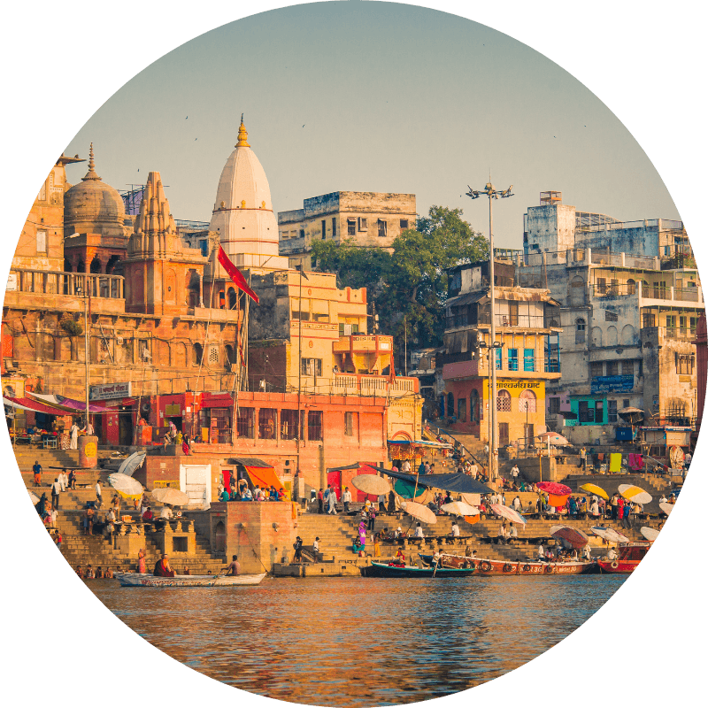 Ghats de Varanasi au coucher du soleil avec temples hindous dorés, bâtiments colorés et fidèles au bord du Gange
