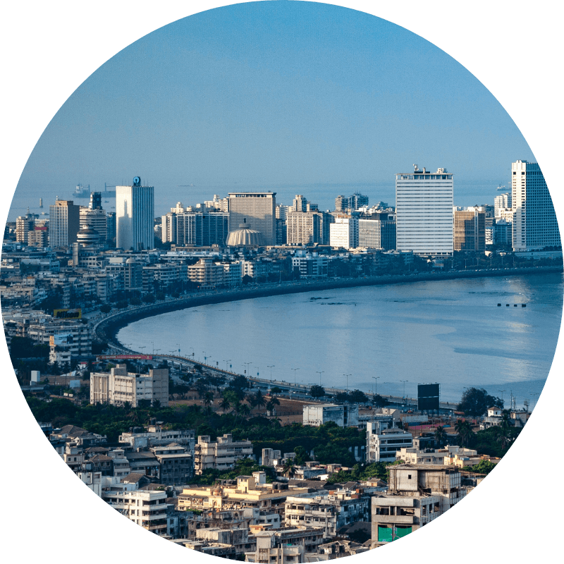 Vue panoramique d'une baie côtière avec gratte-ciel modernes en arrière-plan et quartiers résidentiels en premier plan.